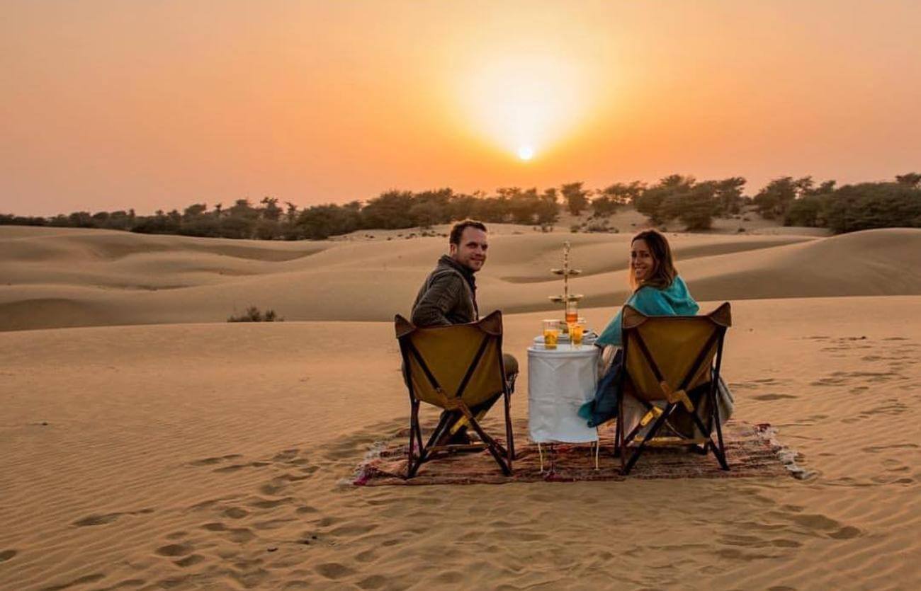 couple having candle light dinner in jaisalmer desert